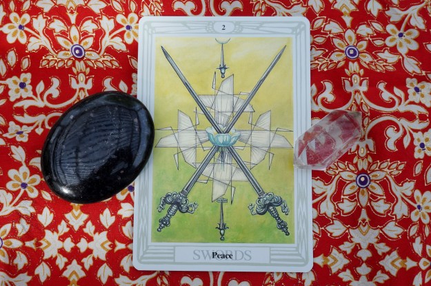 1 tarot card with a black stone and a clear quartz point.
